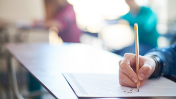 focus is on the hand of a person taking a test with people in the background out of focus