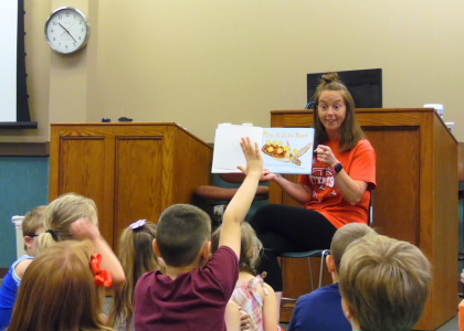 Woman reading a picture book for children sitting on the ground