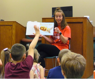 Volunteer reading a picture book to our younger patrons.