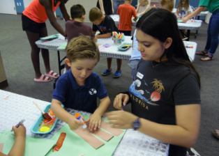 Teen helping younger child with craft