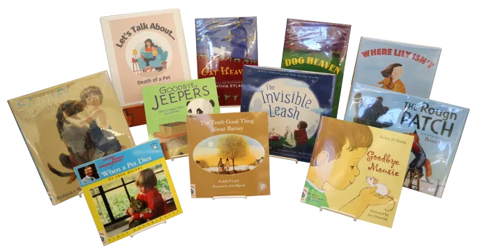 Ten children&#039;s picture books and a binder propped on easels. The binder is labeled &quot;Let&#039;s Talk About... Death of a Pet&quot;