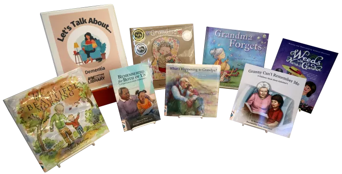 Seven children&#039;s picture books and a binder propped on easels. The binder is labeled &quot;Let&#039;s Talk About... Dementia&quot;