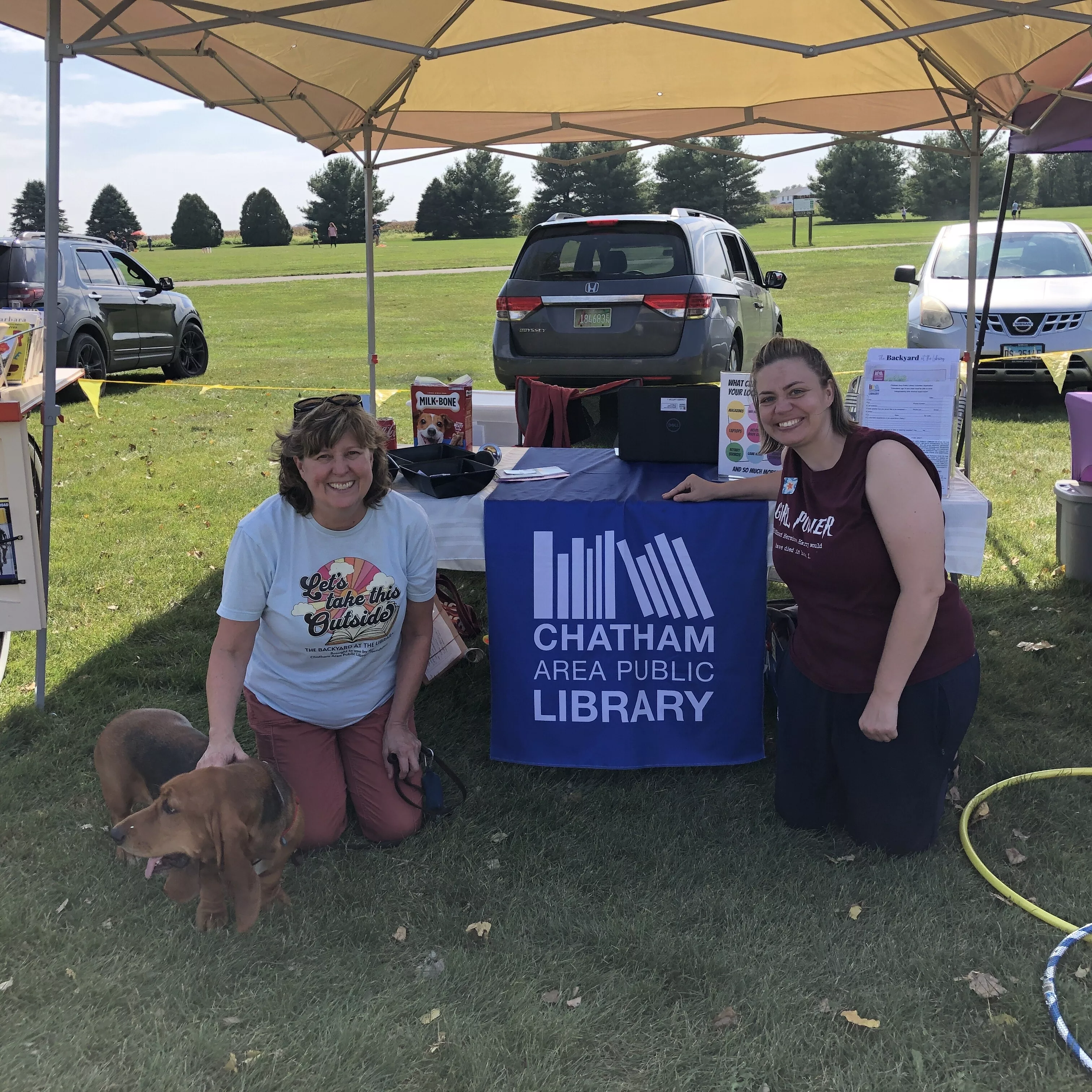 two adults at the Chatham Area Public Library table with dog