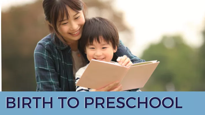 child sitting on lap of parent reading a book